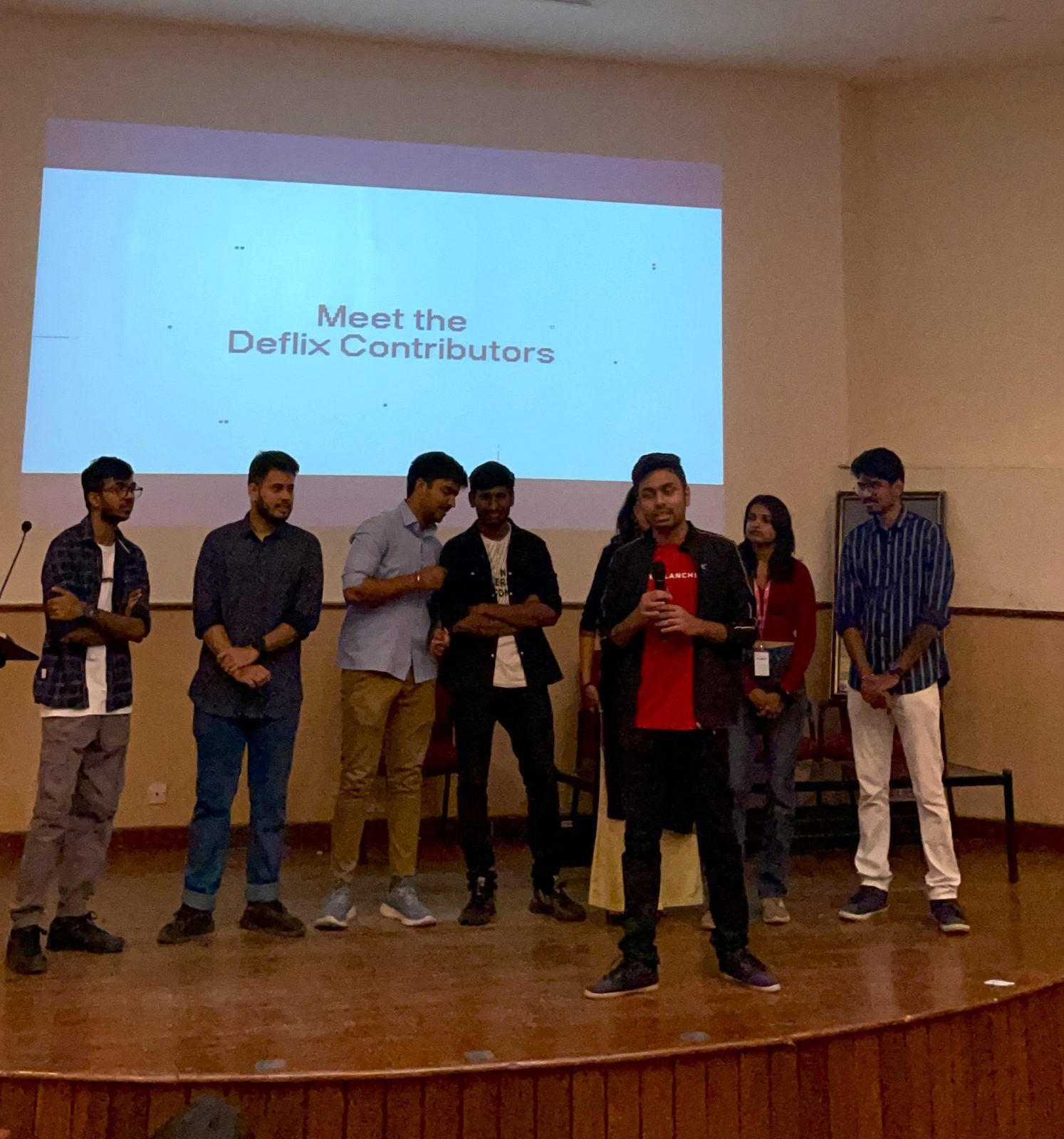 Students on stage under a slide reading Meet the DeFlix Contributors